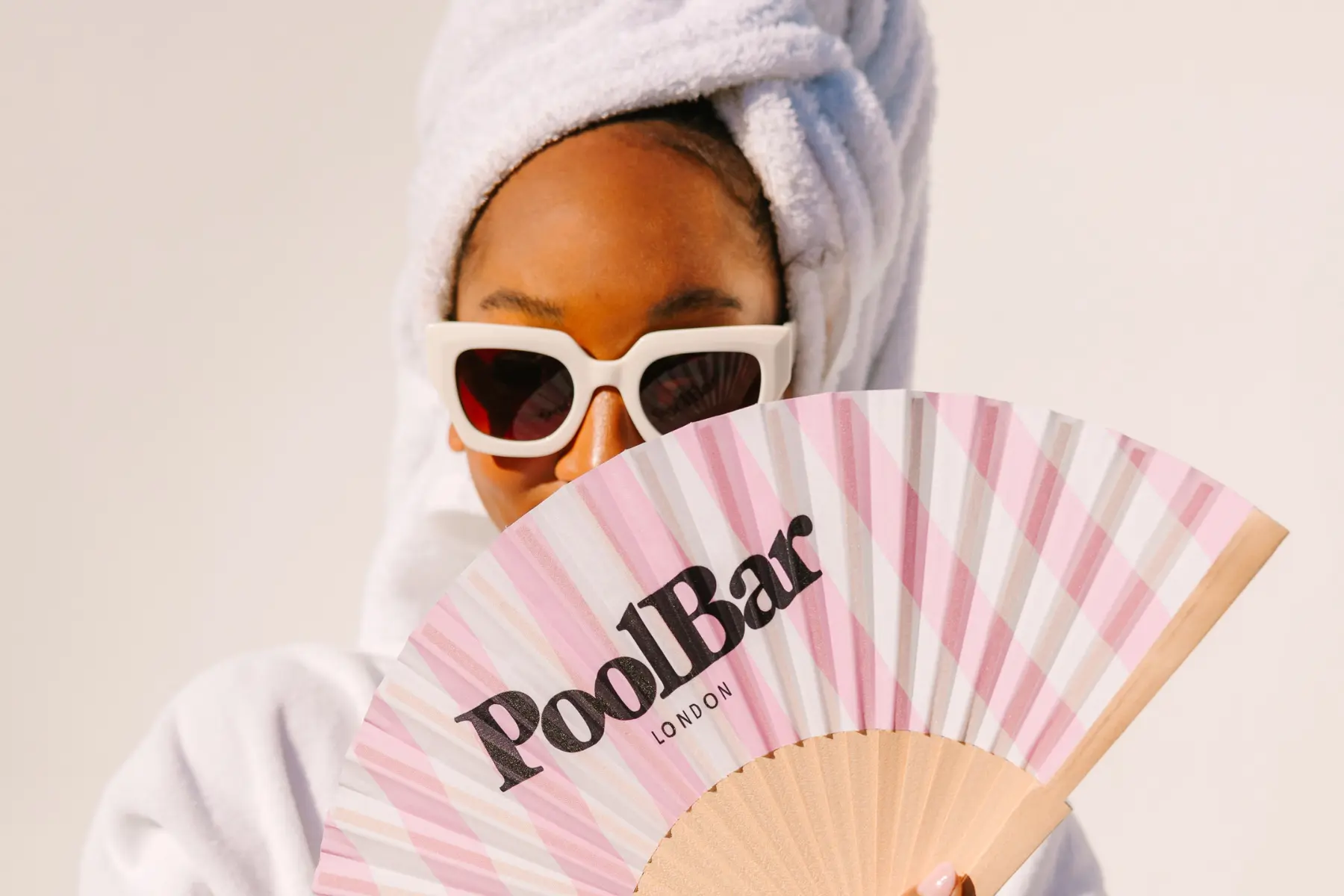 Close up of woman with a hair towel, sunglasses and PoolBar fan
