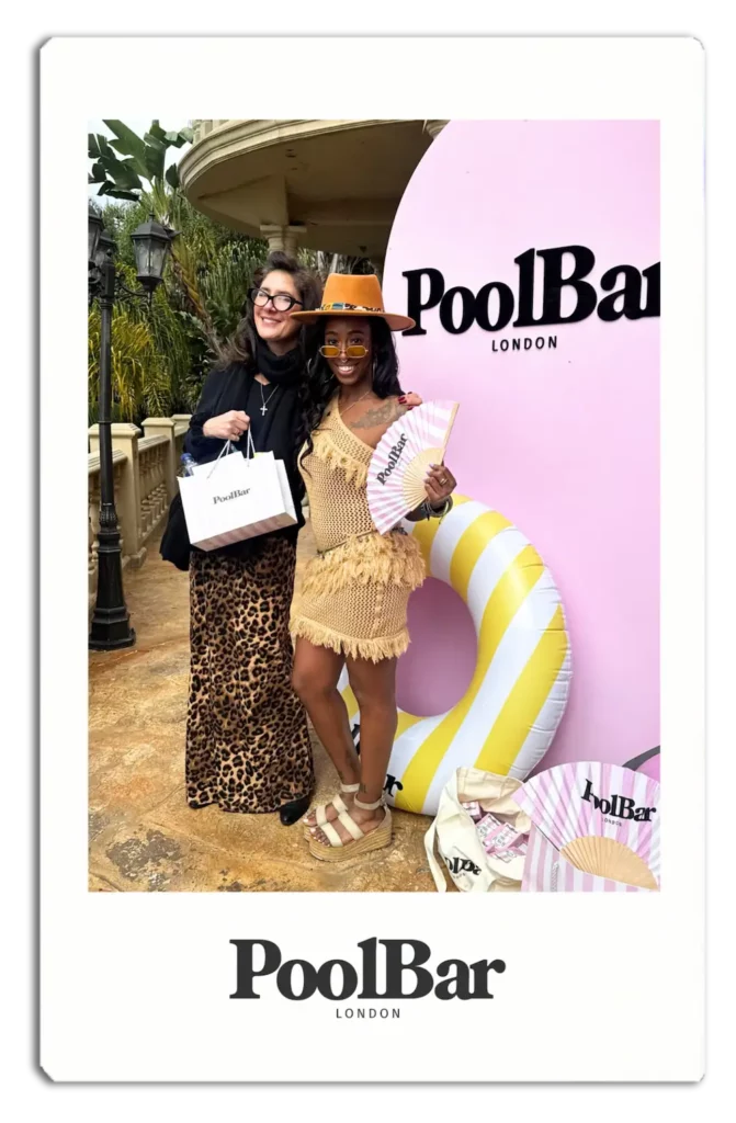2 women posing in front of the poolbar photo stand with giftbag and fan polaroid