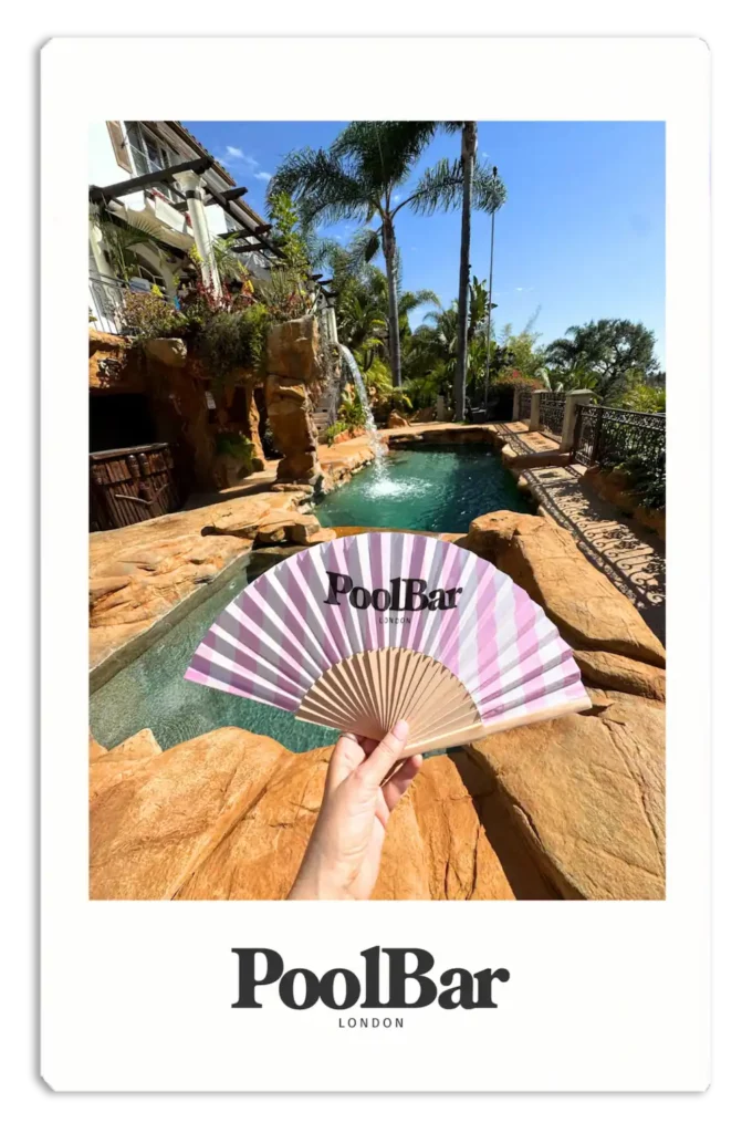 pink and white striped poolbar fan held in front of fountain polaroid