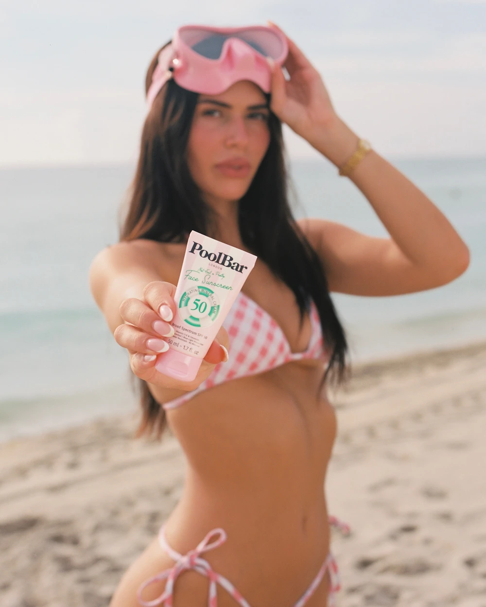 model holding poolbar spf 50 face sunscreen at the beach